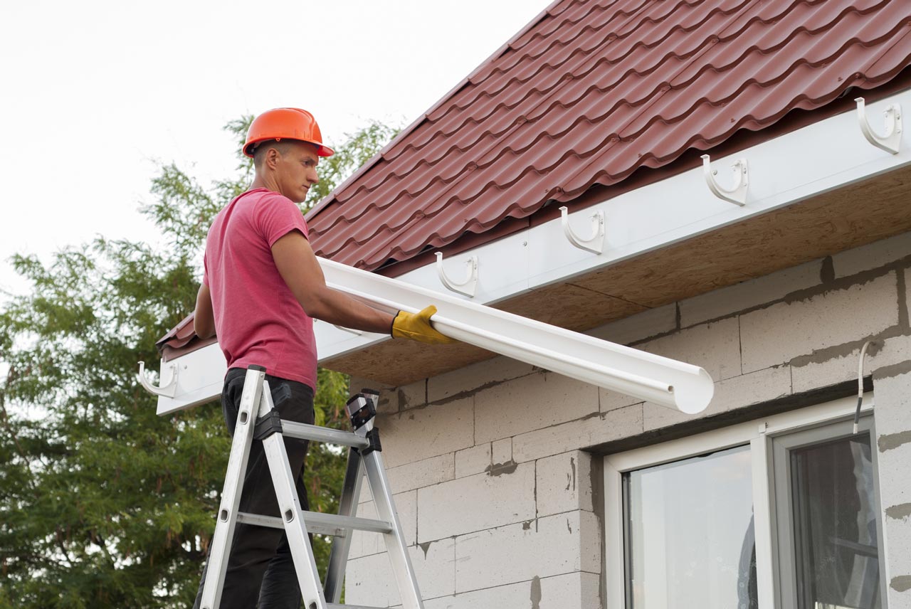 A professional strategically installing gutter system for a residential property
