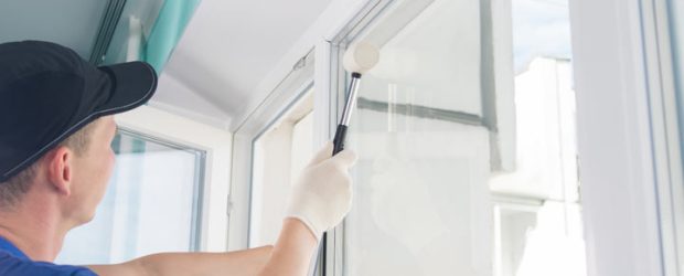 A skilled worker holding a tape measure to assess the dimensions necessary for window installation